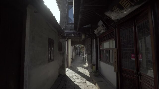 Full length of man walking in narrow lane amidst houses - Suzhou, China
