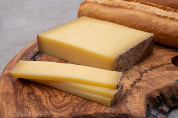 French food -  piece of cheese comte made from cow milk in region Franche-Comte in France and fresh baked baguette bread.