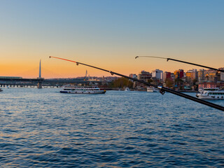 Fototapeta premium Fishing rods at sunset on Galata Bridge in Istanbul, Turkey. Popular hobby and relaxing.