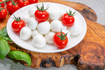 Italian tricolore, small balls of fresh white soft Italian mozzarella cheese, ripe red cherry tomatoes and fresh green basil herb, ready for making caprese salad