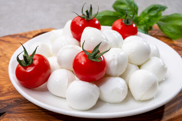 Italian tricolore, small balls of fresh white soft Italian mozzarella cheese, ripe red cherry tomatoes and fresh green basil herb, ready for making caprese salad