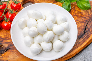Italian tricolore, small balls of fresh white soft Italian mozzarella cheese, ripe red cherry tomatoes and fresh green basil herb, ready for making caprese salad