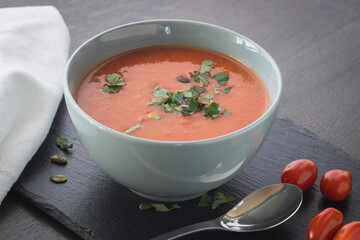 Bowl of red tomato cream soup on wooden table