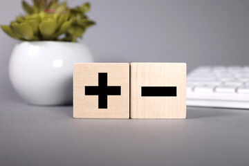 Opposites concept, wooden blog with plus and minus on GRAY background, flat lay, copy space, top...