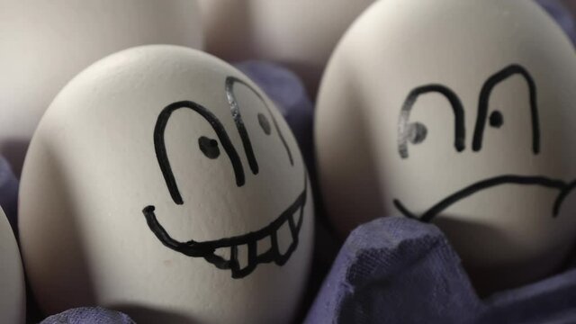 The frown and smiley face on the white eggs on top of the egg tray during the Easter holiday. selective focus.close-up.footage