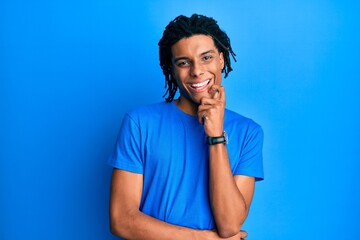 Young african american man wearing casual clothes smiling looking confident at the camera with crossed arms and hand on chin. thinking positive.