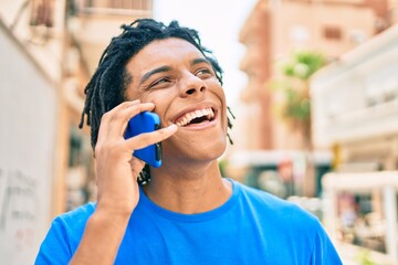 Fototapeta premium Young african american man smiling happy talking on the smartphone at street of city.