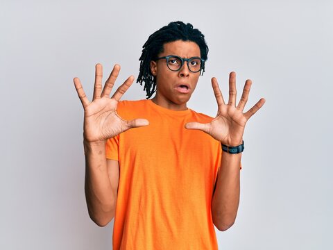 Young african american man wearing casual clothes and glasses afraid and terrified with fear expression stop gesture with hands, shouting in shock. panic concept.