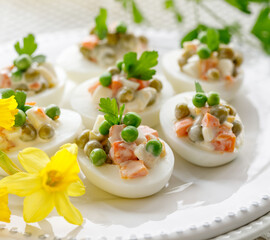 Close up view of boiled eggs stuffed with mayonnaise and vegetable salad served on a white plate. Delicious easter appetizer