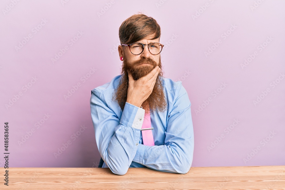 Poster Young irish redhead man wearing business shirt and tie sitting on the table thinking looking tired and bored with depression problems with crossed arms.