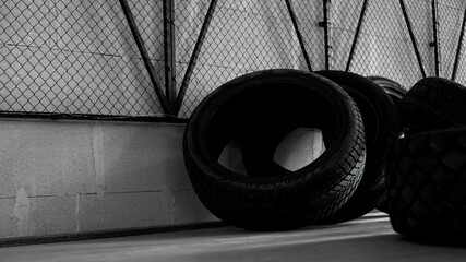 Tire warehouse. Four tires on the concrete floor. Black mesh on the wall.