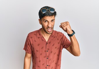 Young handsome man wearing casual summer clothes angry and mad raising fist frustrated and furious while shouting with anger. rage and aggressive concept.