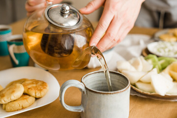 Man pouring black tea into a ceramic mug