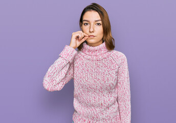 Young caucasian girl wearing wool winter sweater mouth and lips shut as zip with fingers. secret...