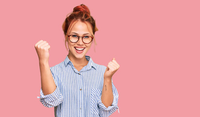 Young redhead woman wearing casual clothes and glasses screaming proud, celebrating victory and...