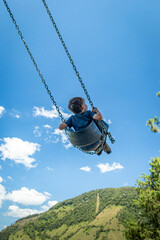 Kind schaukelt in den blauen Himmel
