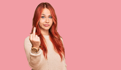 Young redhead woman wearing casual winter sweater showing middle finger, impolite and rude fuck off...
