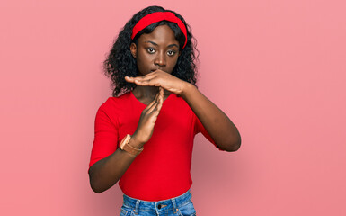 Beautiful african young woman wearing casual clothes doing time out gesture with hands, frustrated...