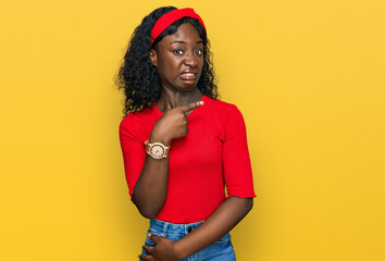 Beautiful african young woman wearing casual clothes pointing aside worried and nervous with...
