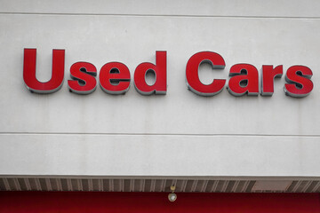 The words, Used Cars in illuminated red letters on a facade wall of a building