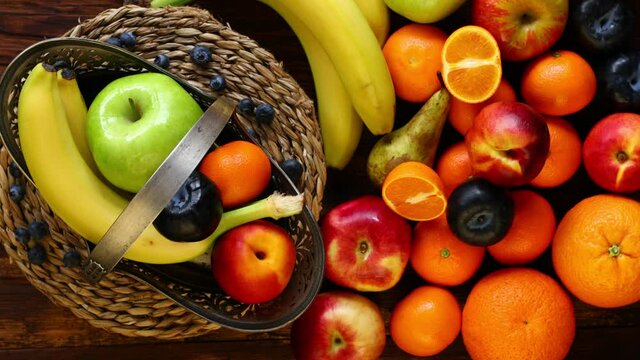 Fresh fruit rolling on a stylish vintage platter next to it on a wooden background is a large amount of fruit. 