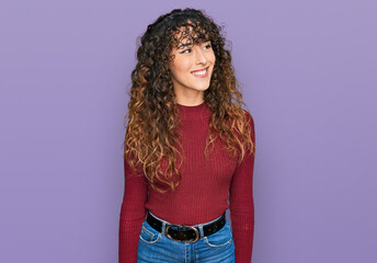 Young hispanic girl wearing casual clothes looking away to side with smile on face, natural expression. laughing confident.