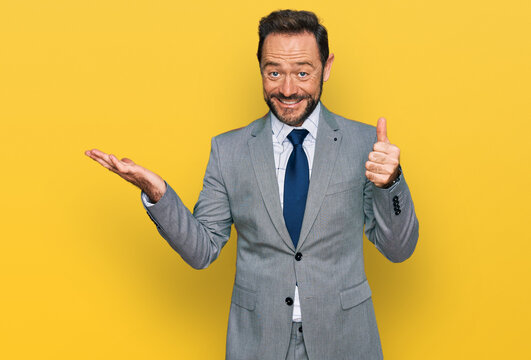 Middle age man wearing business clothes showing palm hand and doing ok gesture with thumbs up, smiling happy and cheerful