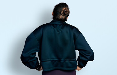 Young hispanic girl wearing sportswear standing backwards looking away with arms on body