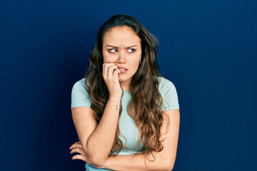 Young hispanic girl wearing casual clothes looking stressed and nervous with hands on mouth biting...