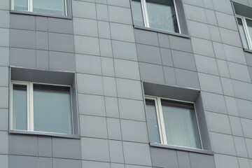 Plastic windows in a modern gray tiled brick high-rise house. Bottom view. Stock photo modern urban development for web and print.