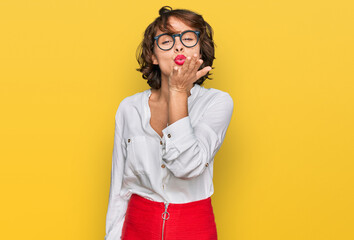 Young hispanic woman wearing business style and glasses looking at the camera blowing a kiss with hand on air being lovely and sexy. love expression.