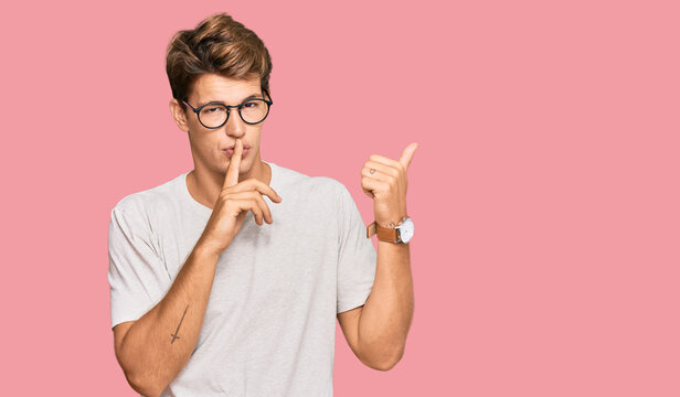 Handsome caucasian man wearing casual clothes and glasses asking to be quiet with finger on lips pointing with hand to the side. silence and secret concept.