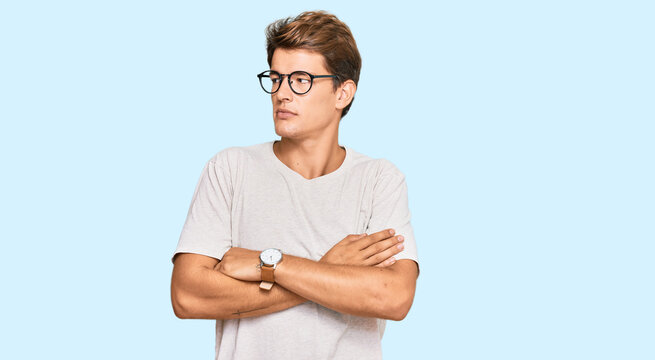 Handsome caucasian man wearing casual clothes and glasses looking to the side with arms crossed convinced and confident