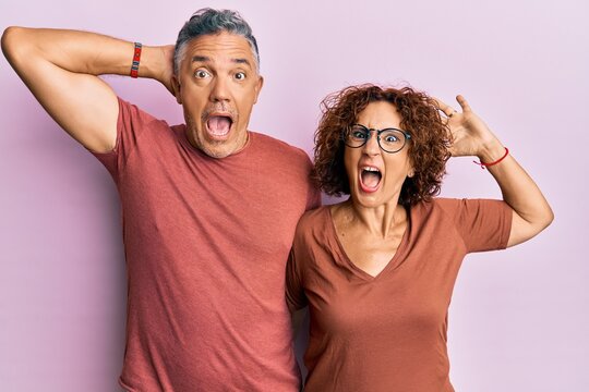 Beautiful middle age couple together wearing casual clothes crazy and scared with hands on head, afraid and surprised of shock with open mouth