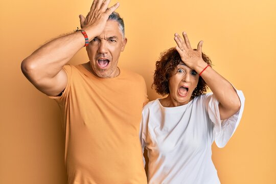 Beautiful middle age couple together wearing casual clothes surprised with hand on head for mistake, remember error. forgot, bad memory concept.