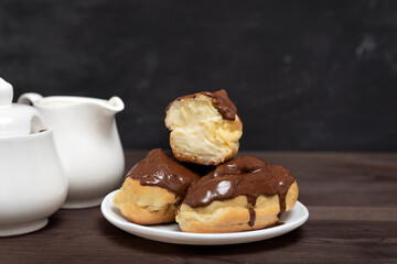 Eclairs with chocolate topping and butter cream on serving plate.