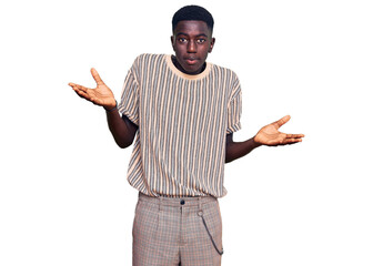 Young african american man wearing casual clothes clueless and confused expression with arms and...