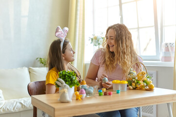 Naklejka premium Mother and her daughter painting eggs. Happy family preparing for Easter.