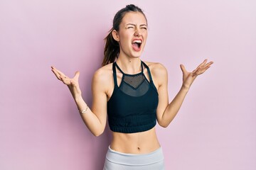 Young brunette woman wearing sportswear crazy and mad shouting and yelling with aggressive expression and arms raised. frustration concept.