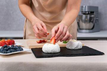 Pastry chef decorates the cakes with strawberries. Process of making confectionery.