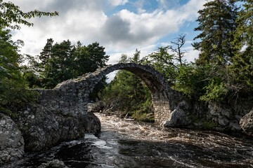 Fototapeta na wymiar Medieval Stone Packhorse Bridge over the Dulnain river, Carrbridge, Scotland