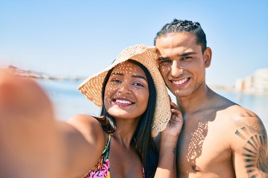 Young latin couple smiling happy making selfie by the camera at the beach.