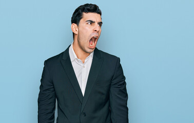 Handsome hispanic man wearing business clothes angry and mad screaming frustrated and furious, shouting with anger. rage and aggressive concept.
