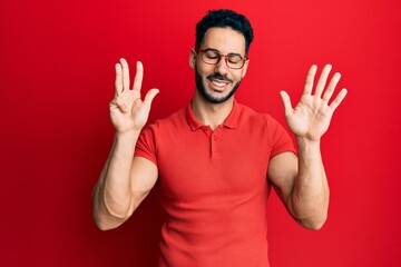 Young hispanic man wearing casual clothes and glasses showing and pointing up with fingers number...