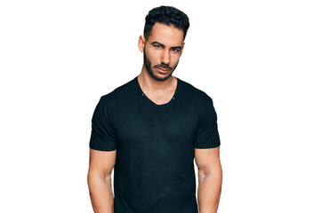 Hispanic man with beard wearing casual black t shirt skeptic and nervous, frowning upset because of...