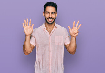 Hispanic man with beard wearing casual shirt showing and pointing up with fingers number nine while...