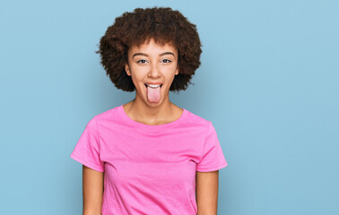 Young hispanic girl wearing casual clothes sticking tongue out happy with funny expression. emotion concept.