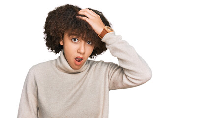 Young hispanic girl wearing wool winter sweater surprised with hand on head for mistake, remember...