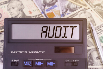 On the table are dollars and a calculator on the electronic board which says AUDIT