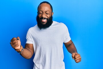 Young african american man wearing casual white tshirt very happy and excited doing winner gesture with arms raised, smiling and screaming for success. celebration concept.